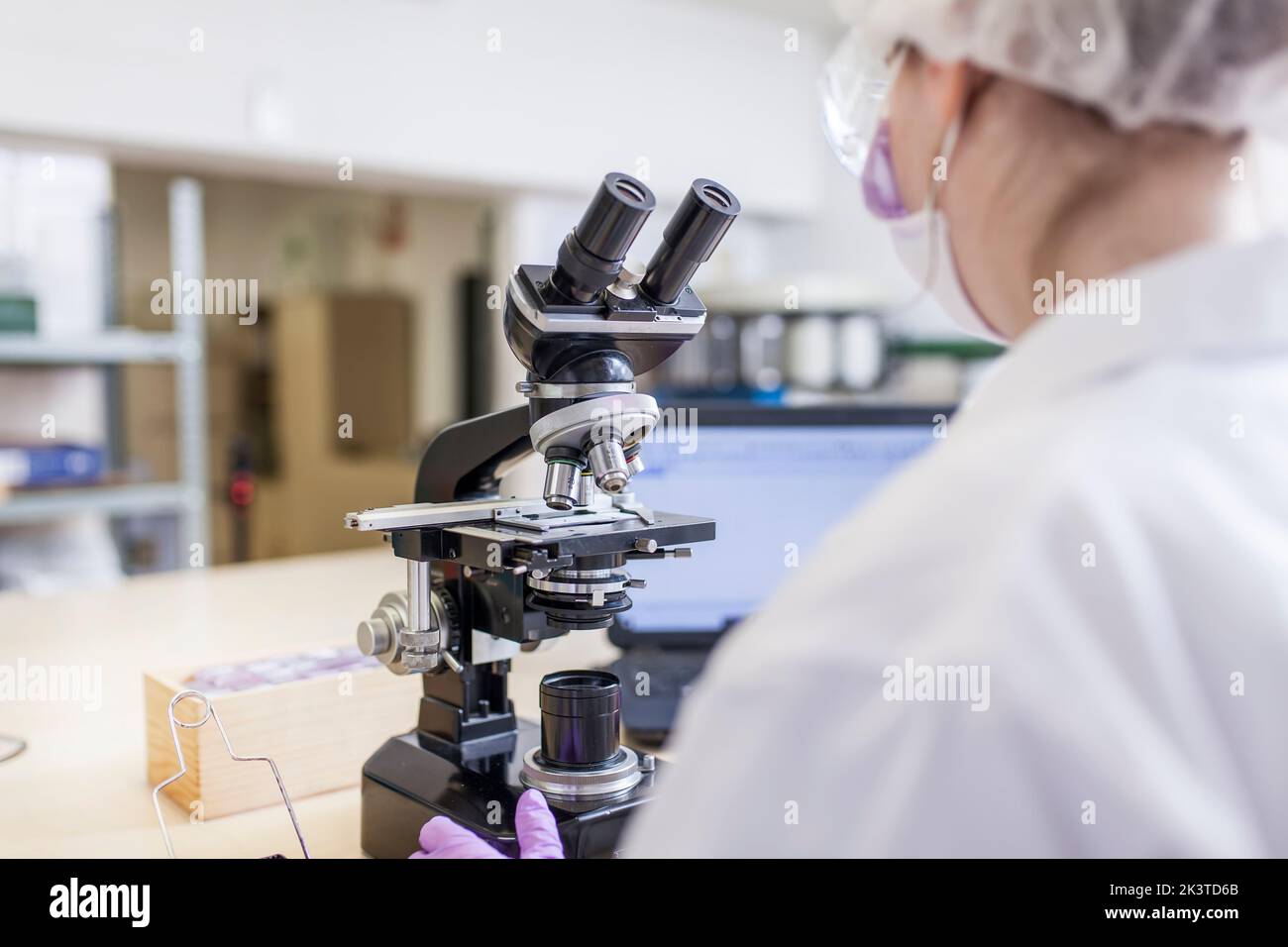 vue arrière d'une femme scientifique anonyme regardant au microscope en laboratoire Banque D'Images