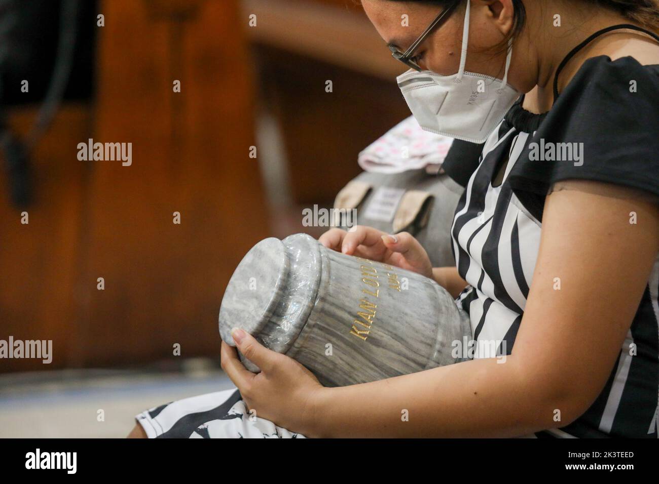 Manille, Philippines. 28th septembre 2022. Krizzhia Loren Rosero, sœur de Kian Lloyd delos Santos, 17 ans, victime de la répression du gouvernement contre la drogue, tient son urne lors d'un service commémoratif à l'intérieur d'une église catholique de la ville de Quezon, dans la région métropolitaine de Manille, aux Philippines. 28 septembre 2022. Les restes ont été exhumés de leurs tombes après que le bail sur les tombes dans un cimetière public qu'ils ont été enterrés a expiré et les parents ne pouvaient pas se permettre de continuer avec elle. (Image de crédit : © Basilio Sepe/ZUMA Press Wire) Banque D'Images