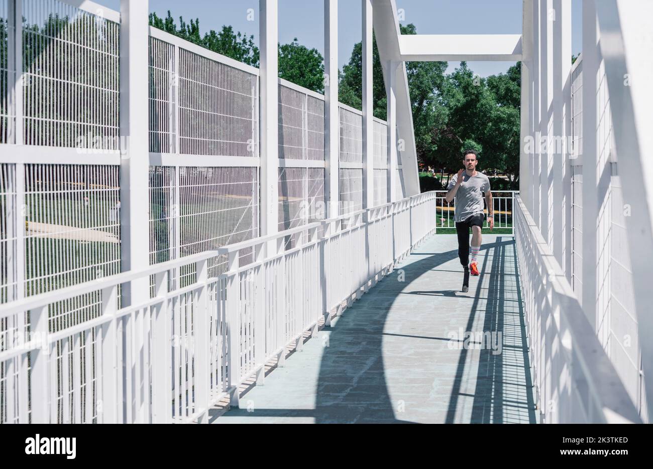 jeune homme avec prothèse de jambe en train de courir sur le pont pendant l'entraînement dans la rue de ville Banque D'Images