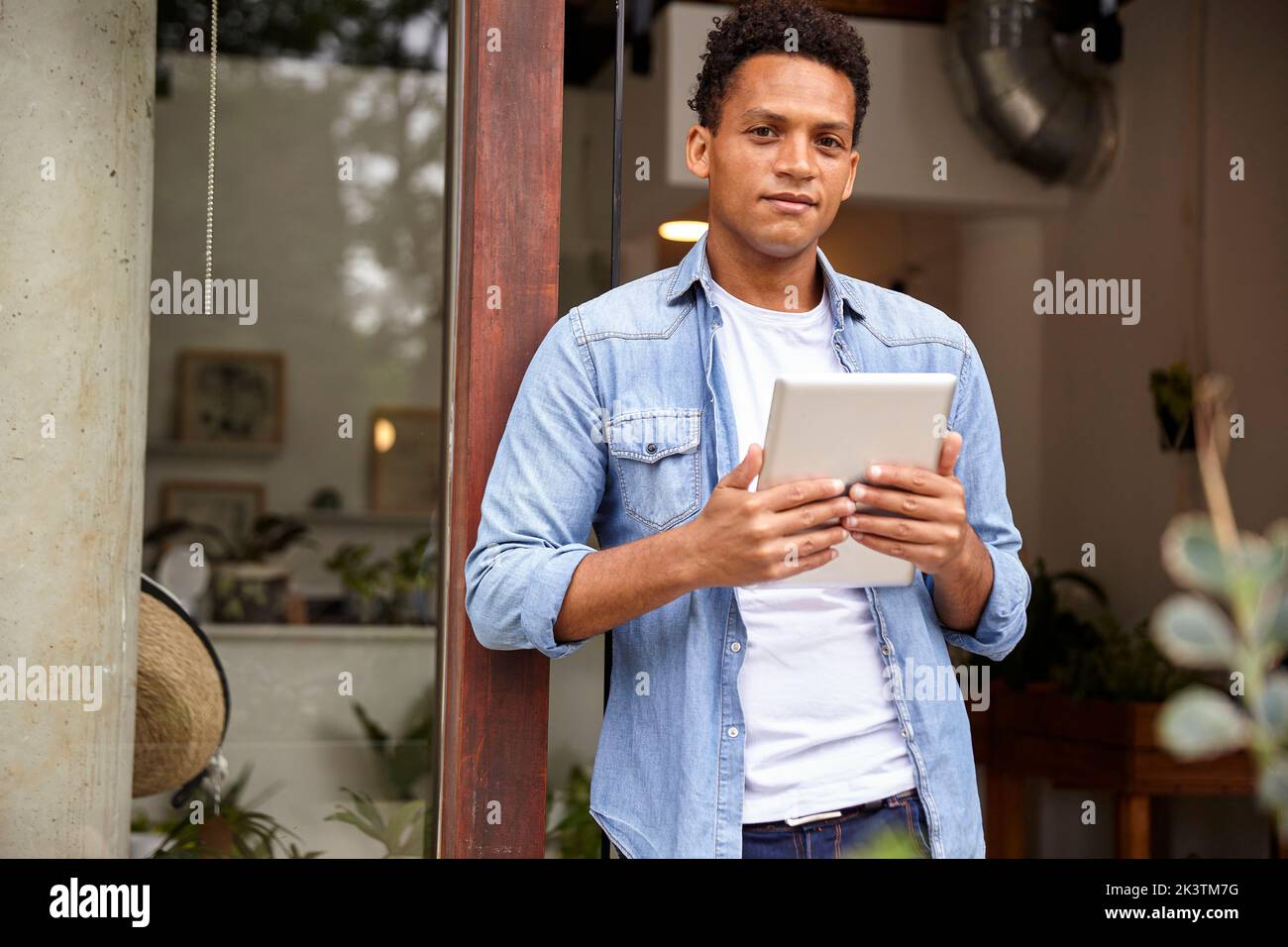Employé d'une pépinière d'Amérique latine tenant une tablette numérique tout en regardant la caméra Banque D'Images