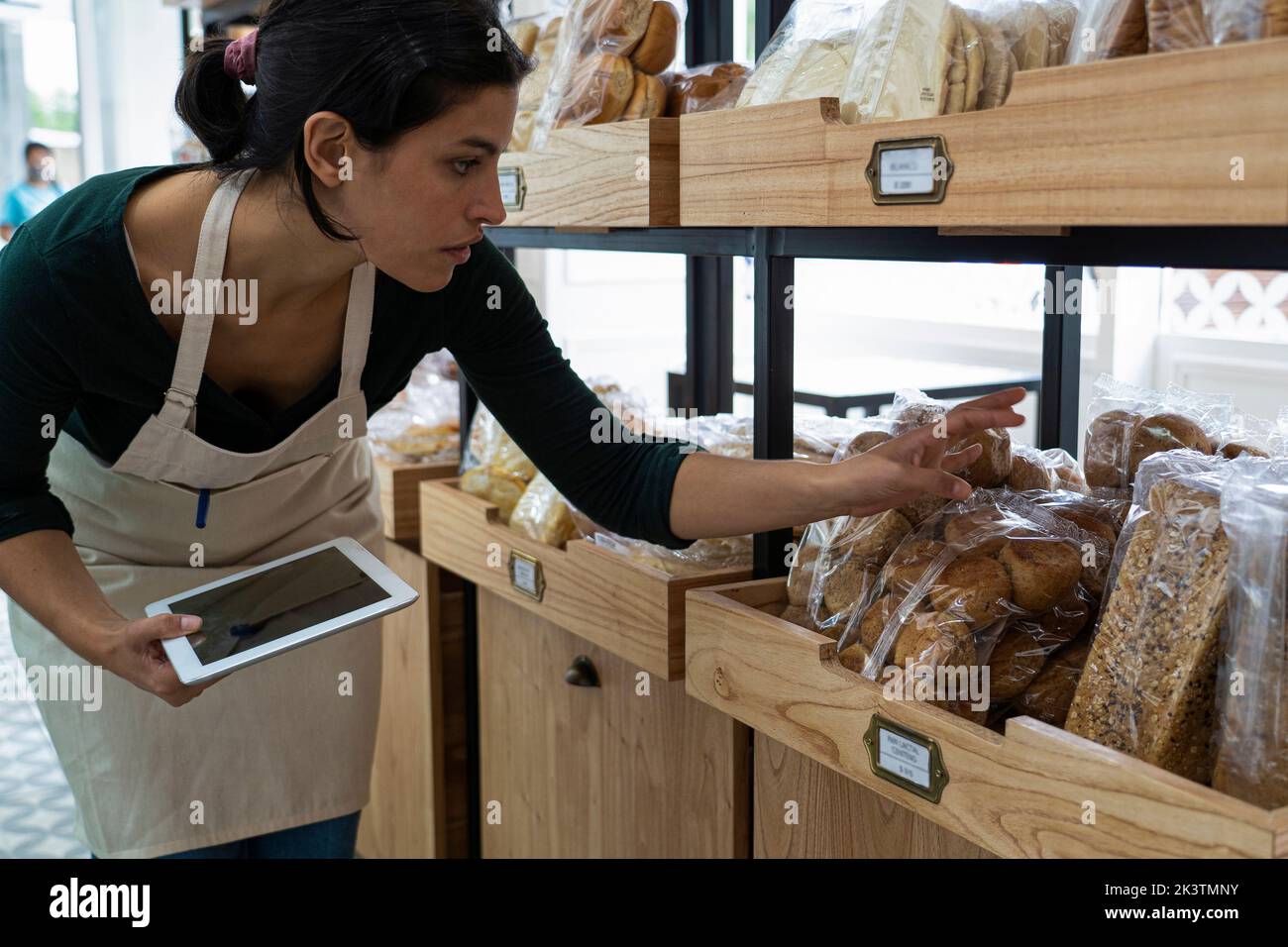 Prise de vue d'une femme propriétaire de boulangerie latino-américaine vérifiant les prix des marchandises Banque D'Images