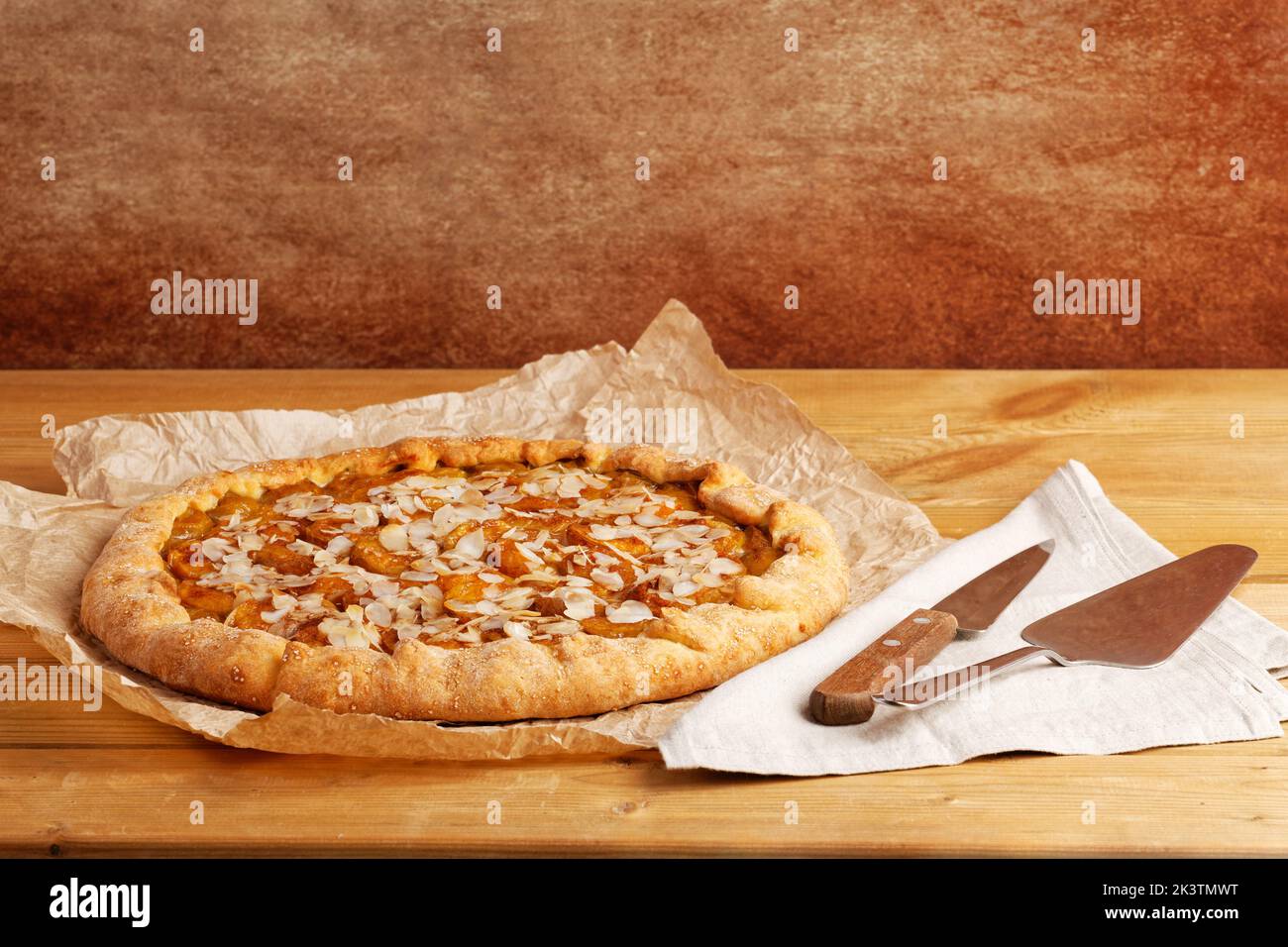 Tarte maison avec prunes et pétales d'amande sur papier parchemin. CopySpace. Banque D'Images Tarte maison avec prunes et pétales d'amande sur papier parchemin. CopySpace. Banque D'Images