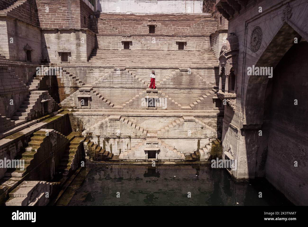 Jeune touriste ethnique se tenant sur les marches de Toorji bien avec de l'eau pendant le tourisme en Inde Banque D'Images