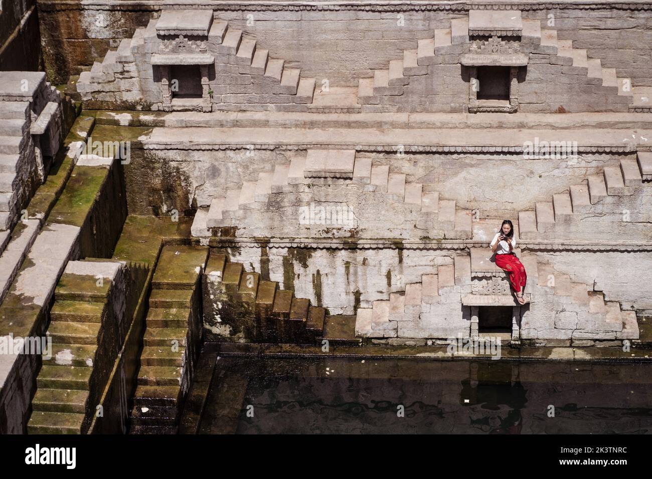 D'en haut, jeune touriste ethnique assis sur les marches de Toorji bien avec de l'eau pendant le tourisme en Inde Banque D'Images