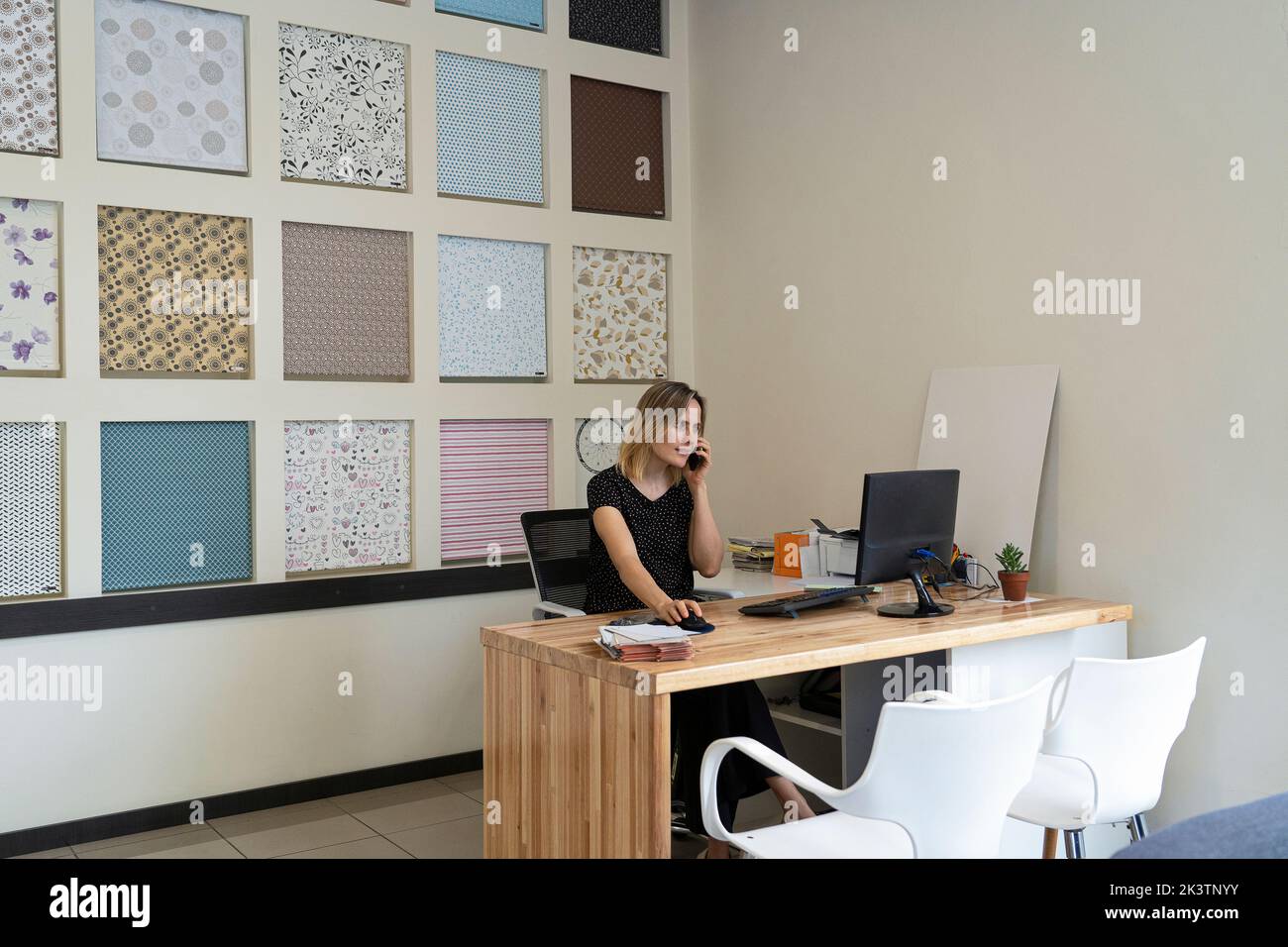 Vue grand angle d'une femme entrepreneure de design d'intérieur qui parle au téléphone à son bureau Banque D'Images