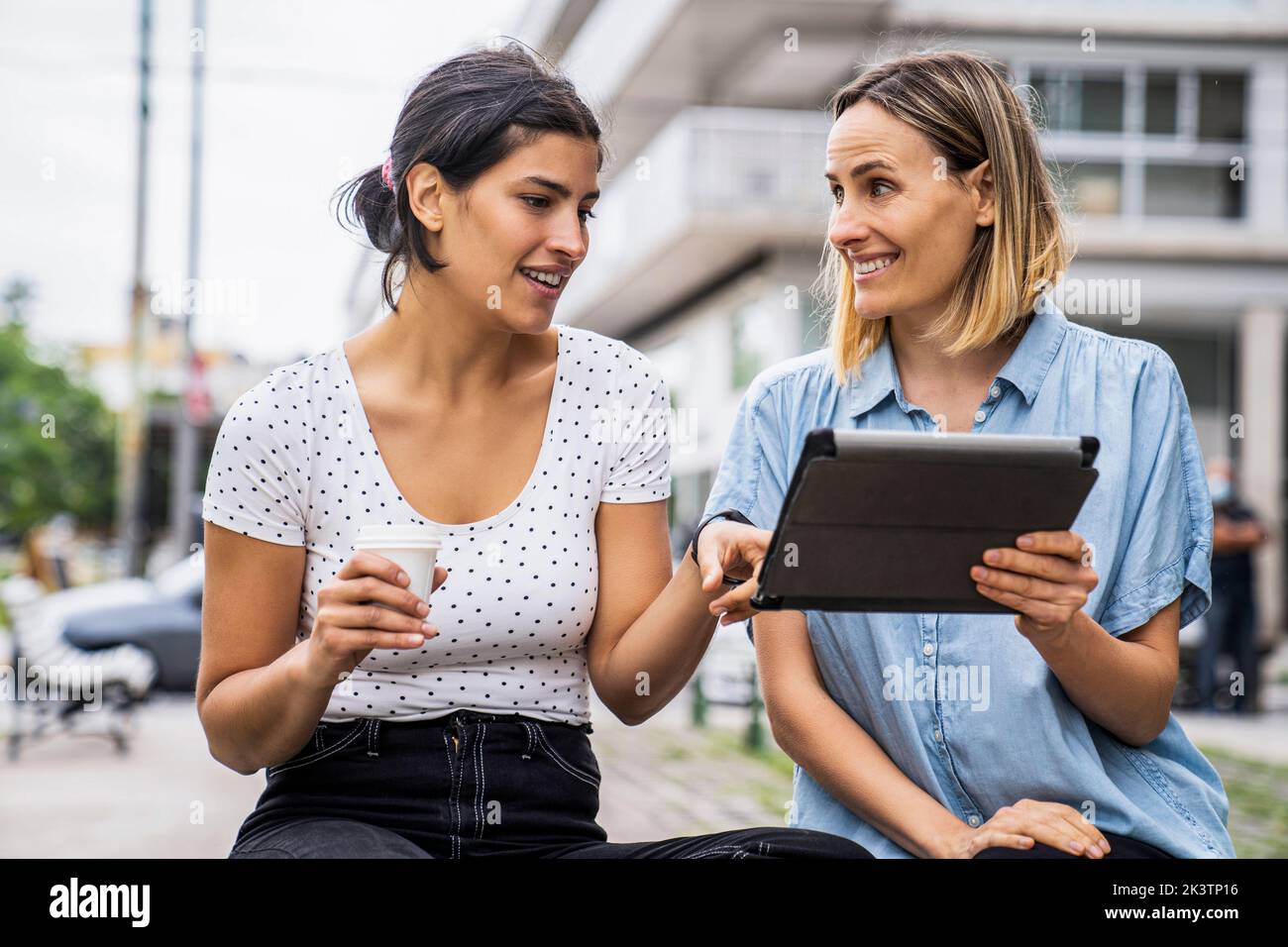 Vue de face deux collègues féminins qui parlent de questions de travail en travaillant à l'extérieur Banque D'Images