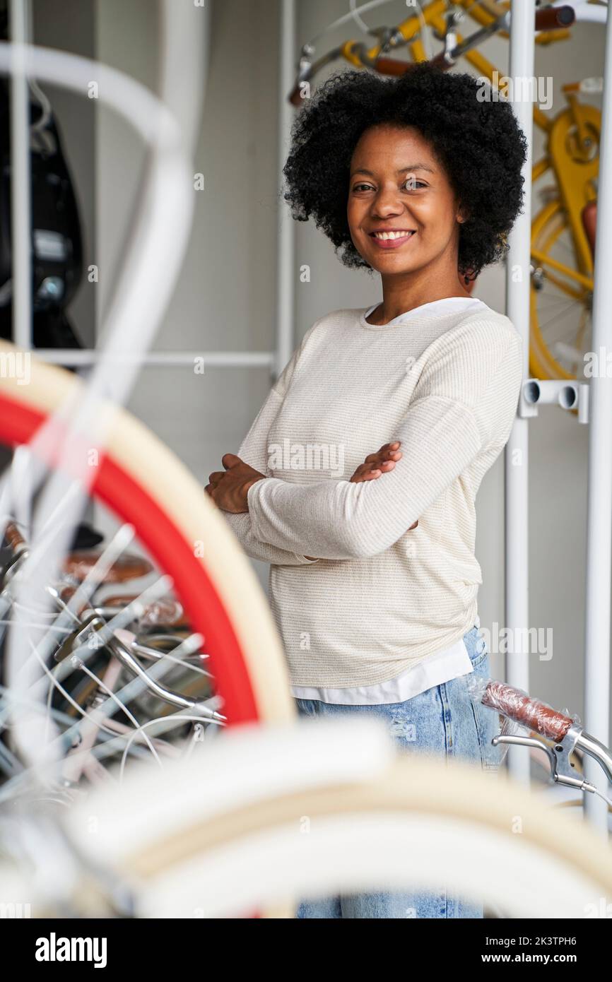 Portrait moyen de la propriétaire d'une cycliste afro-américaine souriant devant un appareil photo placé à l'intérieur de son magasin Banque D'Images