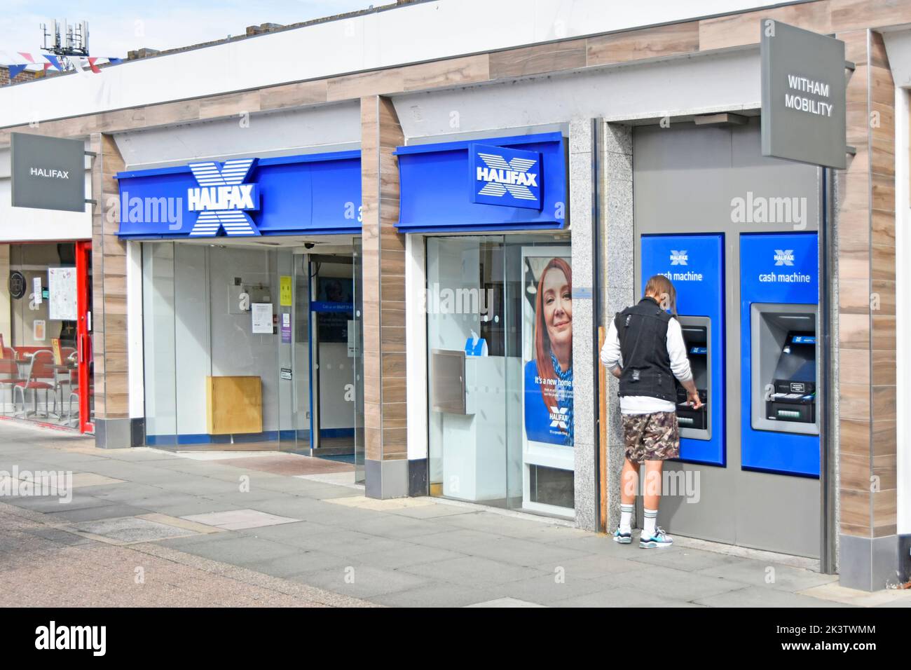 Façade Halifax Building Society maintenant seulement Halifax et une partie de la banque Lloyds vue arrière client utilisant l'une des deux distributeurs automatiques de billets Witham Essex Angleterre Banque D'Images