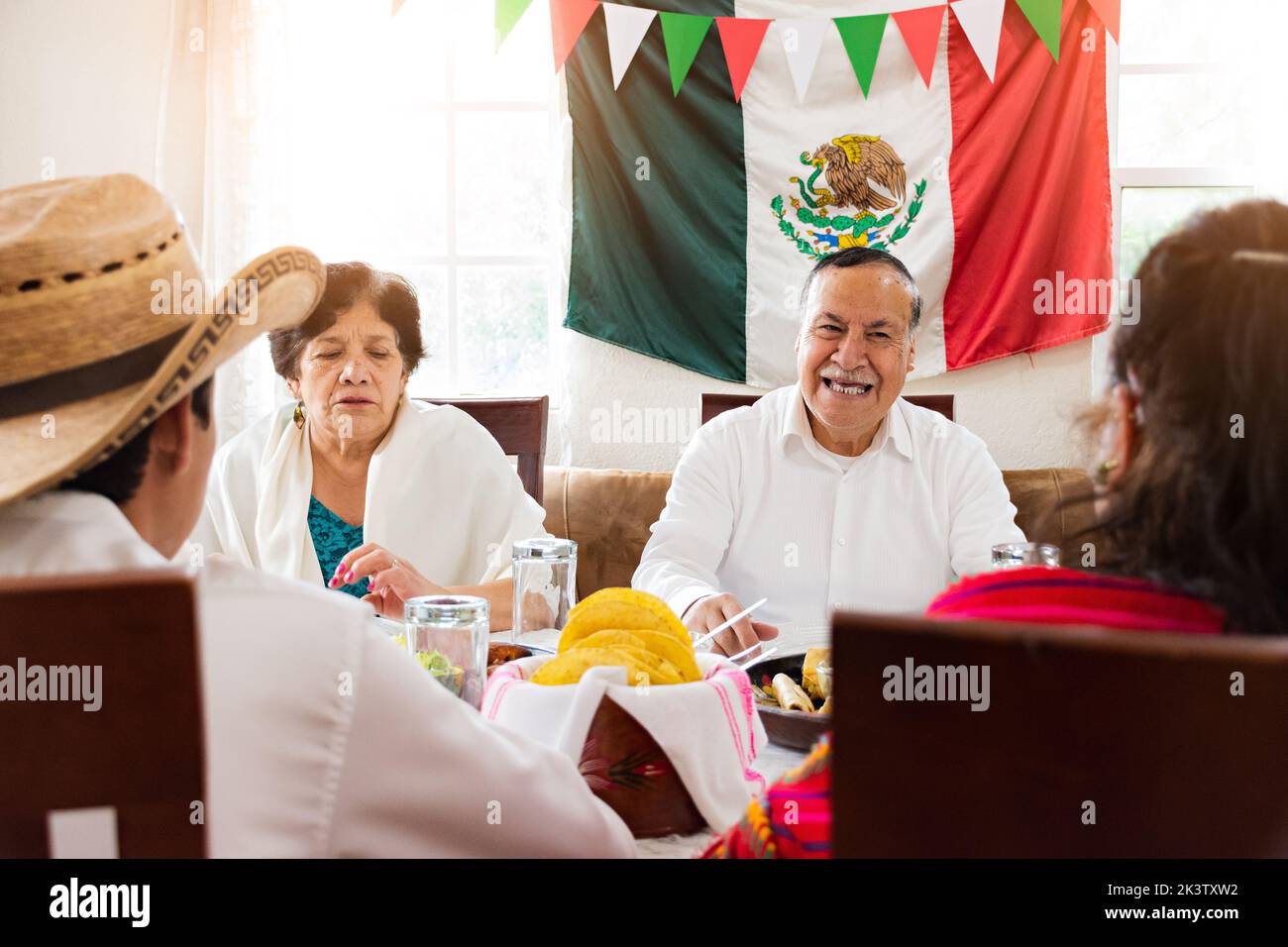 Ravie les hommes et les femmes latino-américains assis à table et riant à blague pendant le déjeuner traditionnel à la maison Banque D'Images