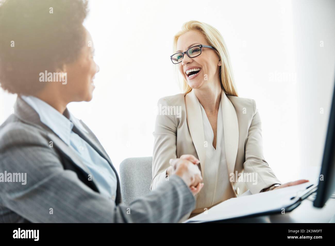 Bonne jeune femme d'affaires qui se fait la main avec un client au bureau Banque D'Images