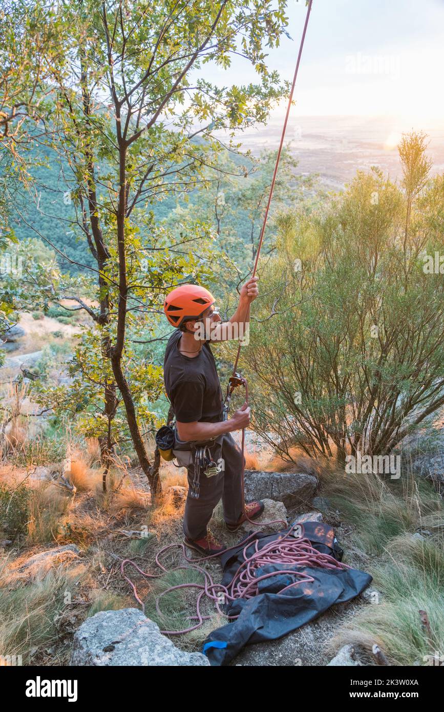 Par dessus le grimpeur actif qualifié assurant le partenaire tenant la corde sur la colline à la montagne dans les arbres Banque D'Images