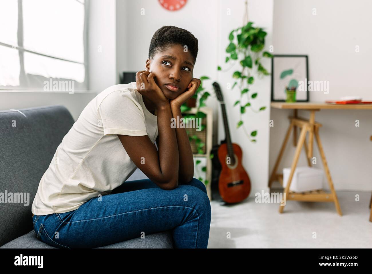 Une jeune femme africaine inquiète, assise seule sur un canapé, pensant aux problèmes Banque D'Images