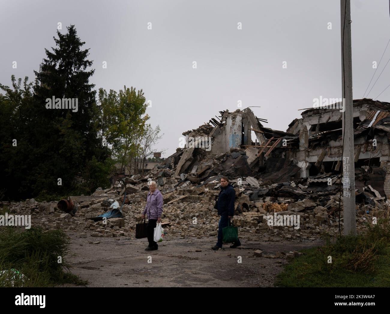 Les résidents d'Izyum sont vus marcher à côté d'un bâtiment endommagé. Il y a trois semaines, les troupes ukrainiennes ont libéré Izyum et d'autres zones stratégiques clés de la région de Kharkiv. Les résidents retournent lentement à la normalité malgré des signes d'occupants russes toujours dans la ville et la ville reste à court d'eau, d'électricité et de gaz. Banque D'Images