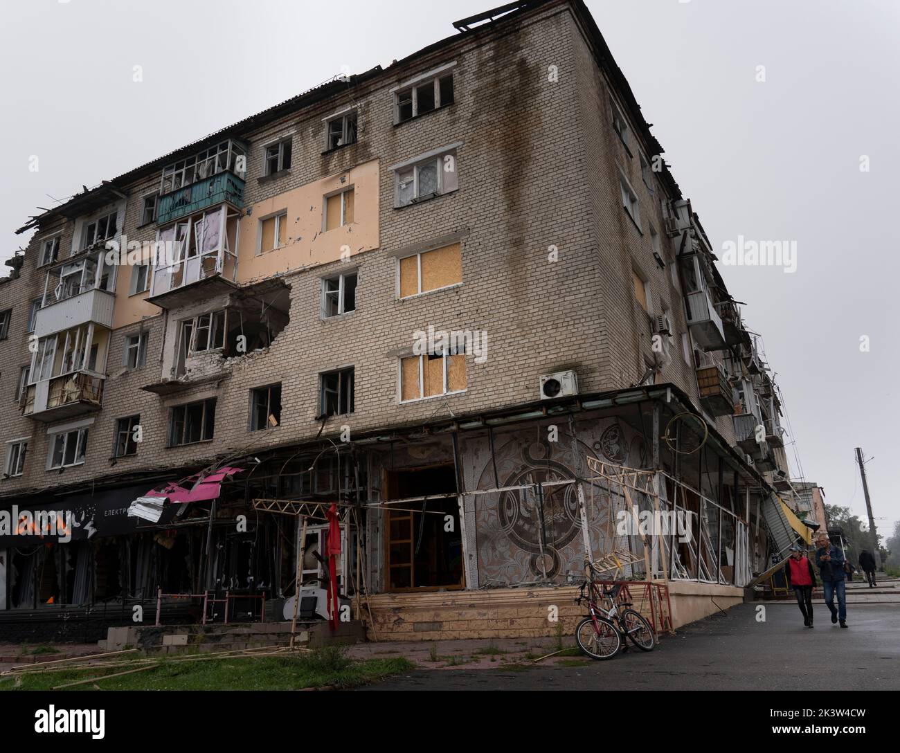 On a vu des résidents d'Izyum marcher à côté d'un bâtiment endommagé. Il y a trois semaines, les troupes ukrainiennes ont libéré Izyum et d'autres zones stratégiques clés de la région de Kharkiv. Les résidents retournent lentement à la normalité malgré des signes d'occupants russes toujours dans la ville et la ville reste à court d'eau, d'électricité et de gaz. Banque D'Images