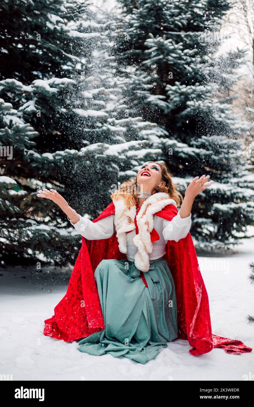 Une belle femme dans une forêt de conifères enneigée jette de la neige Banque D'Images