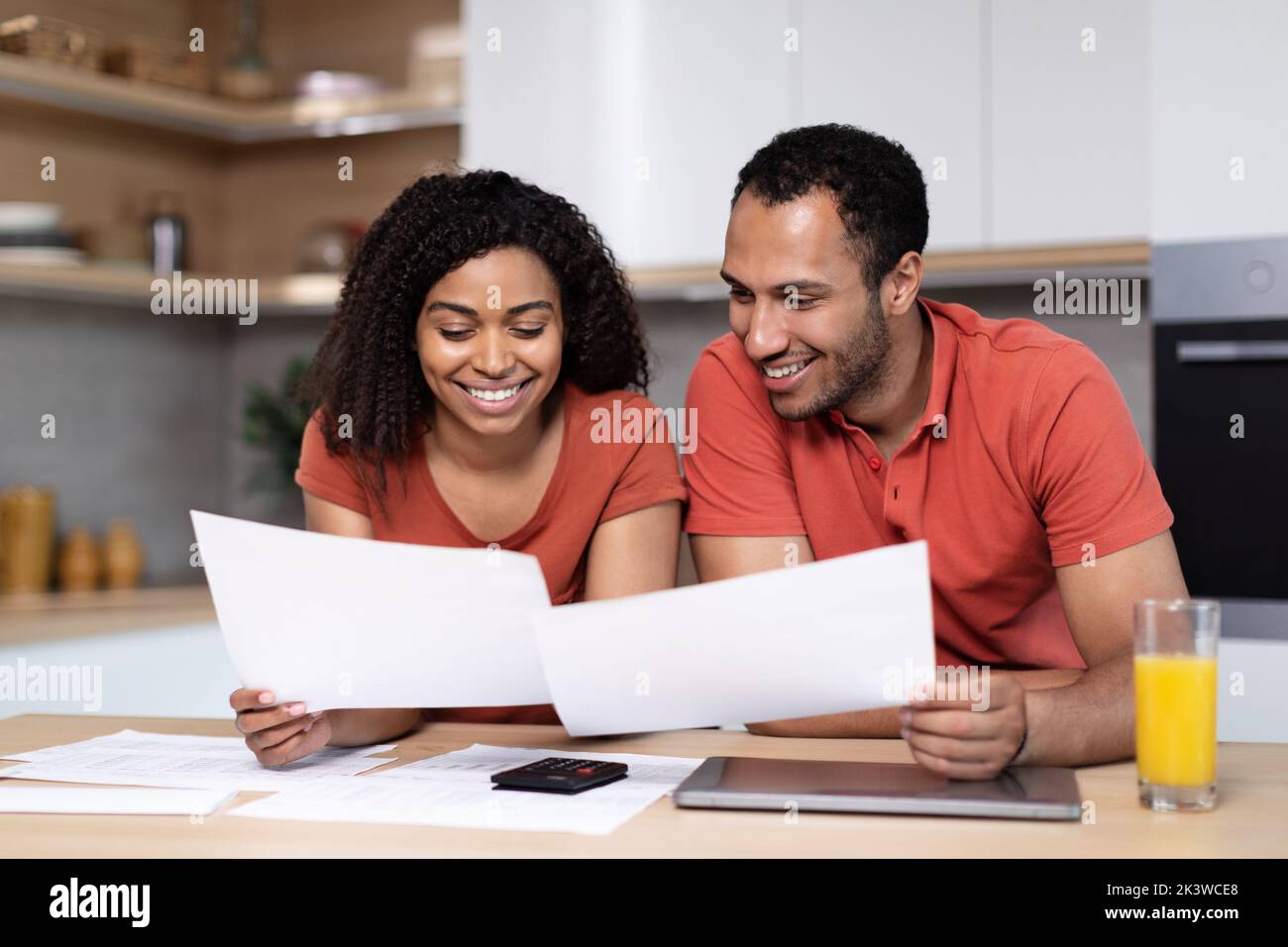 Joyeux jeune couple noir avec des factures de paiement de tablette et les taxes, travailler avec des documents dans l'intérieur de la cuisine Banque D'Images