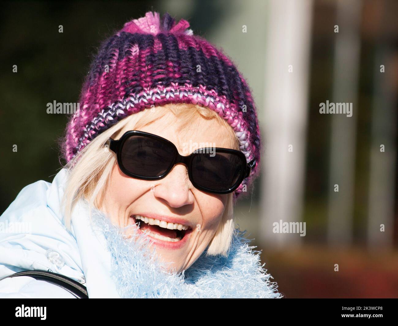 Femme mûre fraiser avec soleil et capuchon violet Banque D'Images