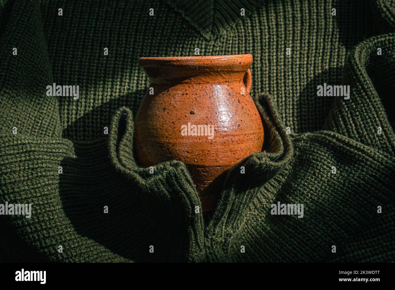 Image d'un pull vert militaire tricoté tenant une tasse en céramique Banque D'Images