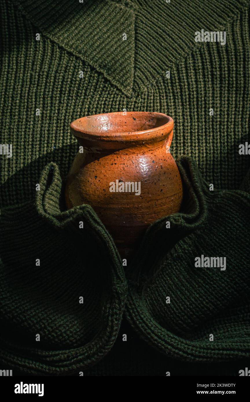 Image verticale d'un pull vert militaire tricoté tenant une tasse en céramique Banque D'Images