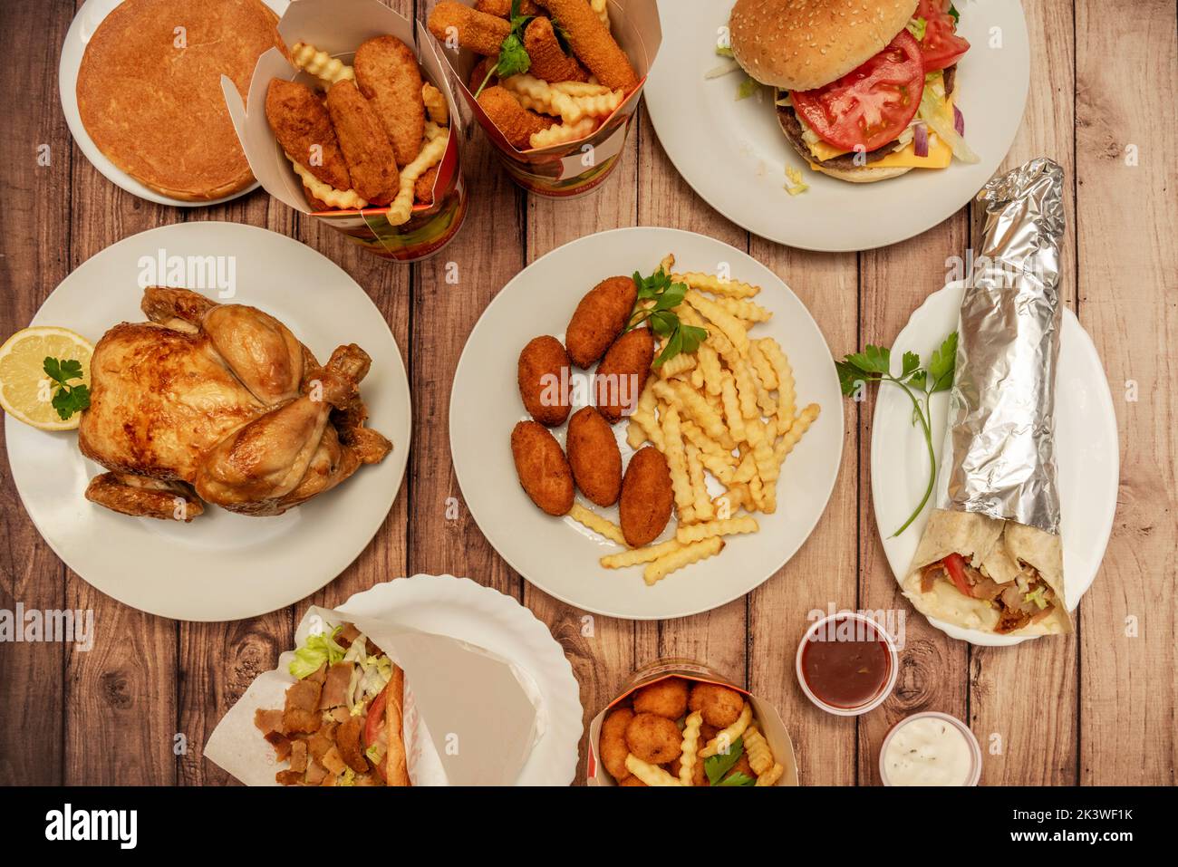 Divers plats de restauration rapide avec croquettes, poulet grillé, boîtes avec pommes de terre et lanières de poulet frites, sandwich au kebab d'agneau et blé dur avec viande halal Banque D'Images