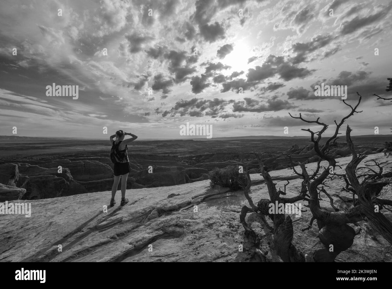 Une femme bénéficie de vues lointaines depuis un point élevé sur le parc Natioal d'Arches, dans l'Utah, aux États-Unis Banque D'Images
