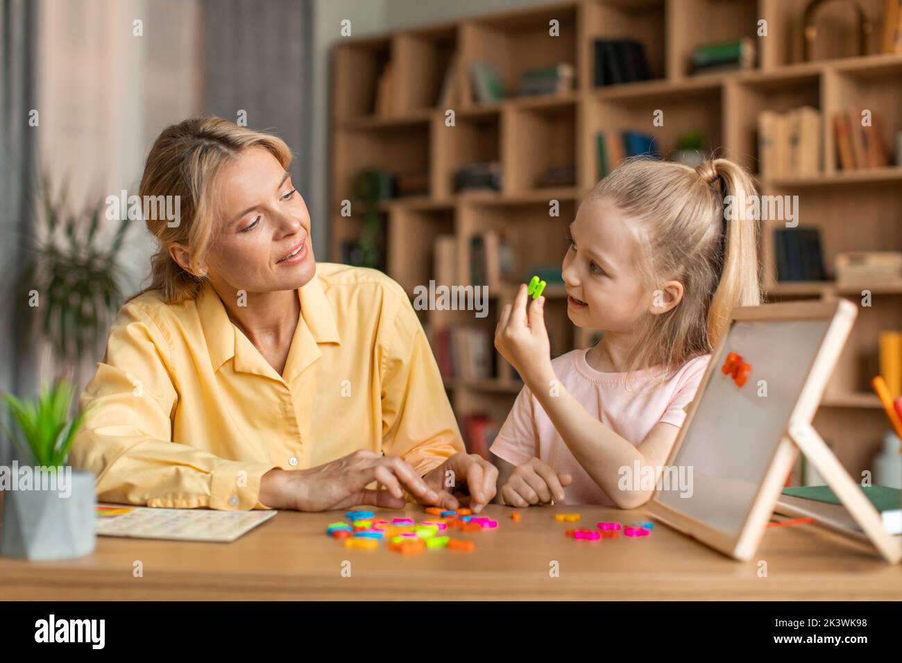 Classes de langue étrangère pour les enfants d'âge préscolaire. Jolie petite fille intelligente apprenant l'alphabet, prononçant et faisant des mots Banque D'Images