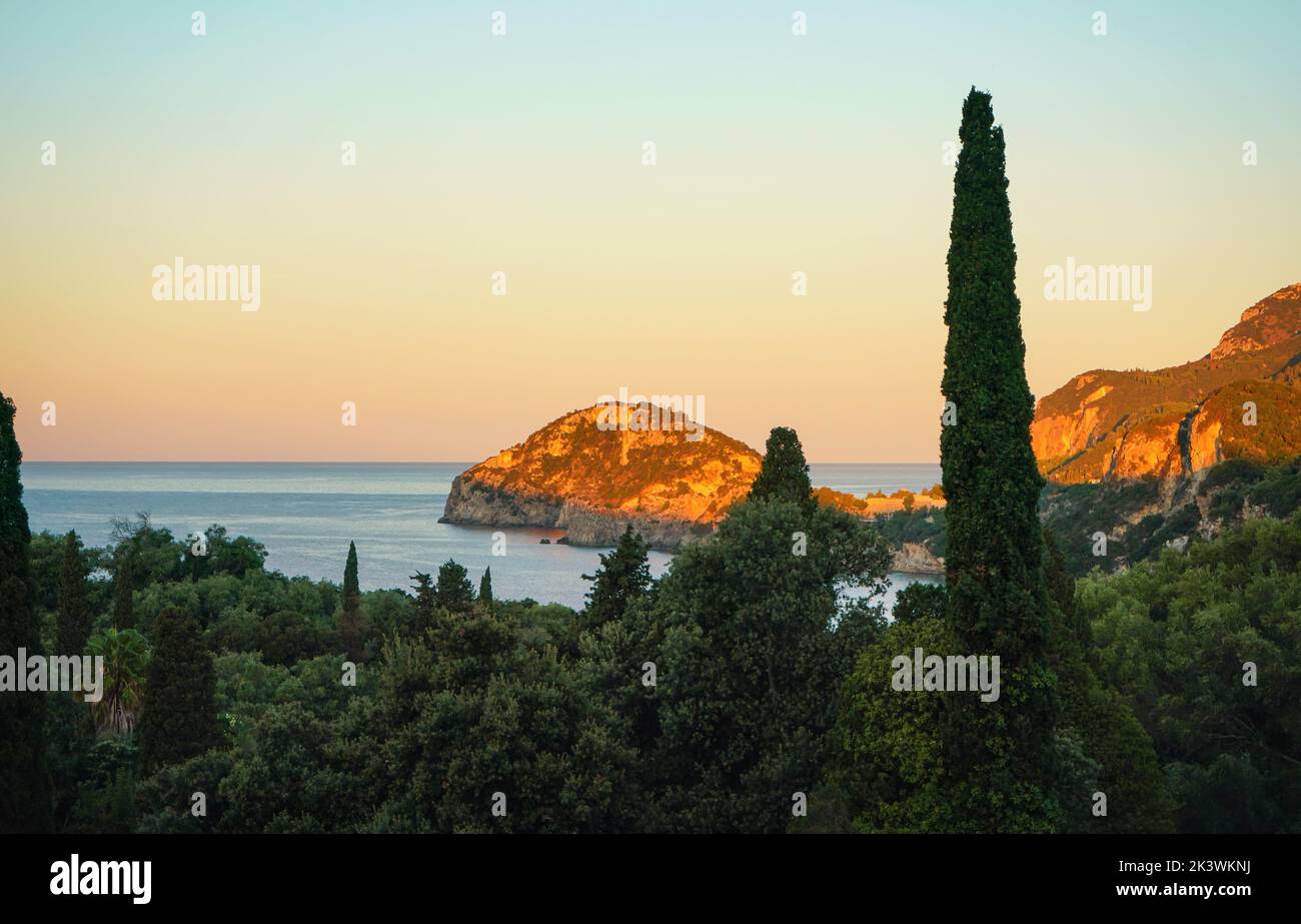 Le soleil du matin brille sur les collines près de la baie de Liapades à Corfou, de grands arbres en premier plan. Lever du soleil sur la côte Banque D'Images