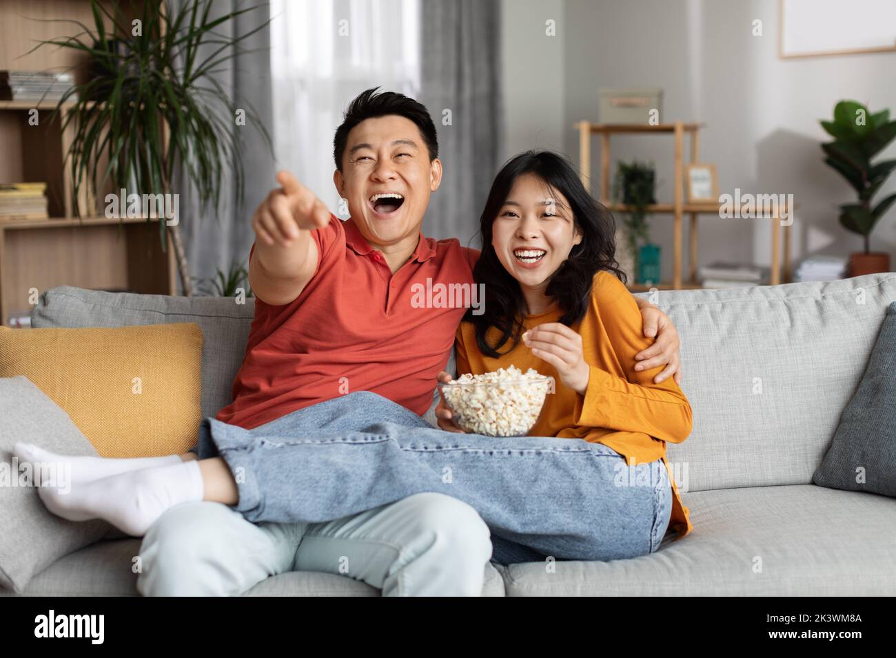 Couple chinois amoureux regardant un film de comédie ensemble à la maison Banque D'Images
