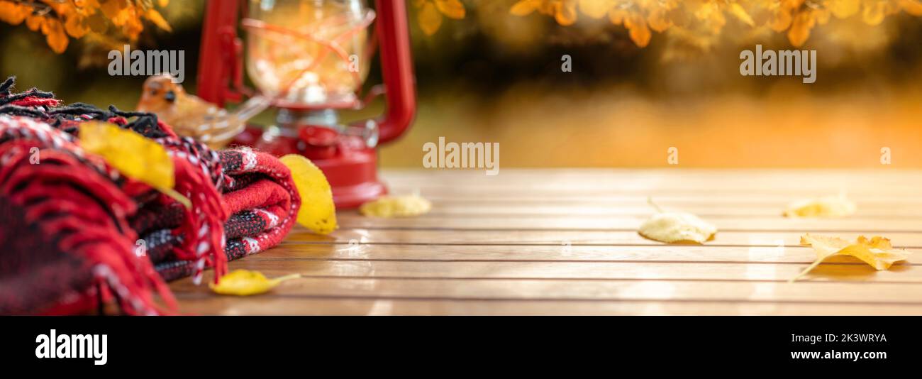 Composition d'automne. Couverture rouge laineux chaude, lanterne, décorations, feuilles d'automne sur table en bois. Scène d'automne le jour ensoleillé dans le jardin d'automne. Automne b Banque D'Images