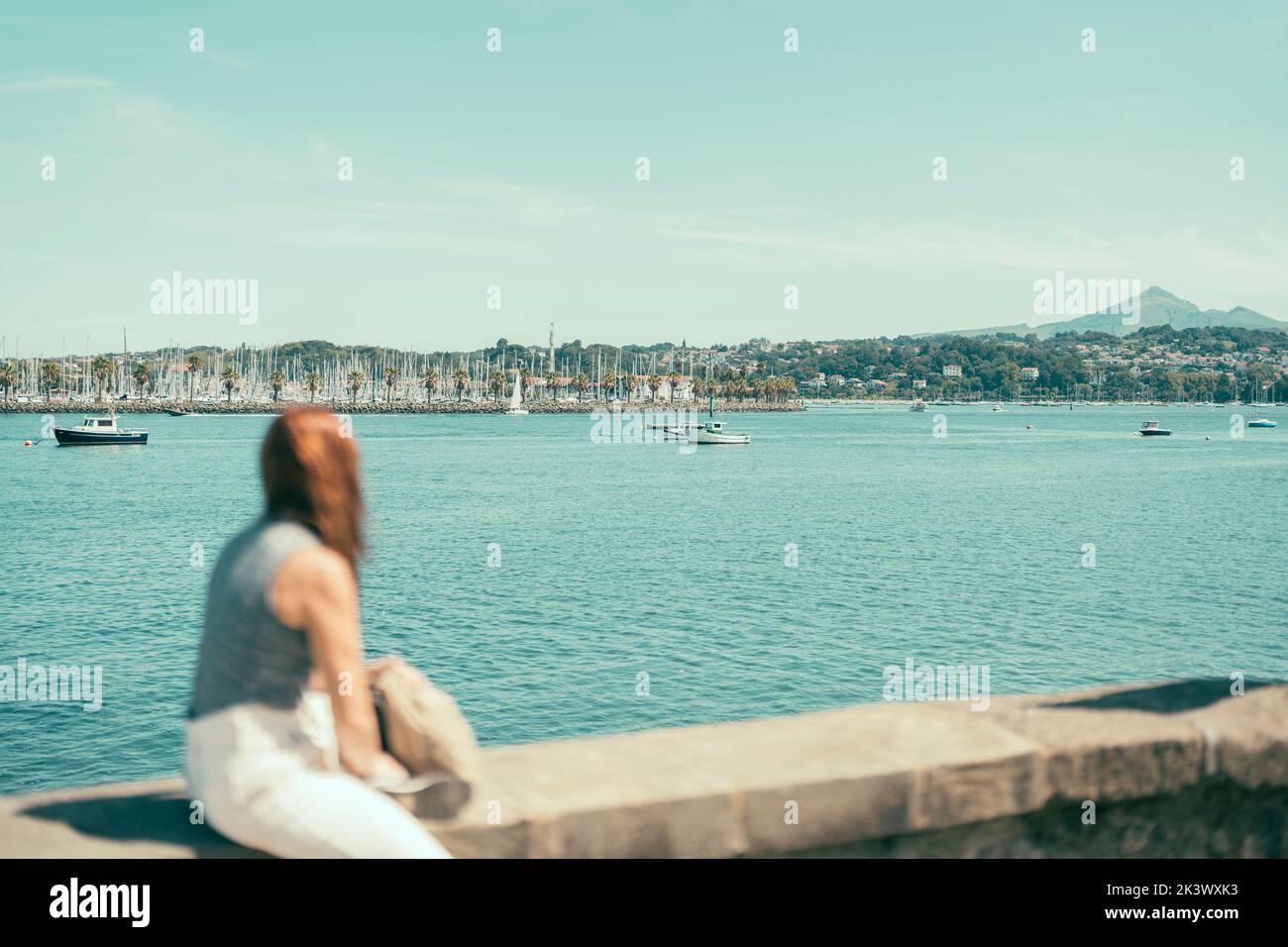 femme hors foyer observant une baie avec des navires de mer Banque D'Images