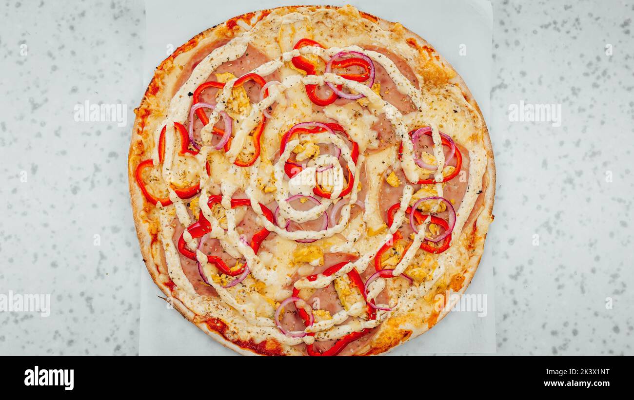 Une vue de dessus de pizza au jambon et à l'oignon avec poivron rouge et sauce Banque D'Images