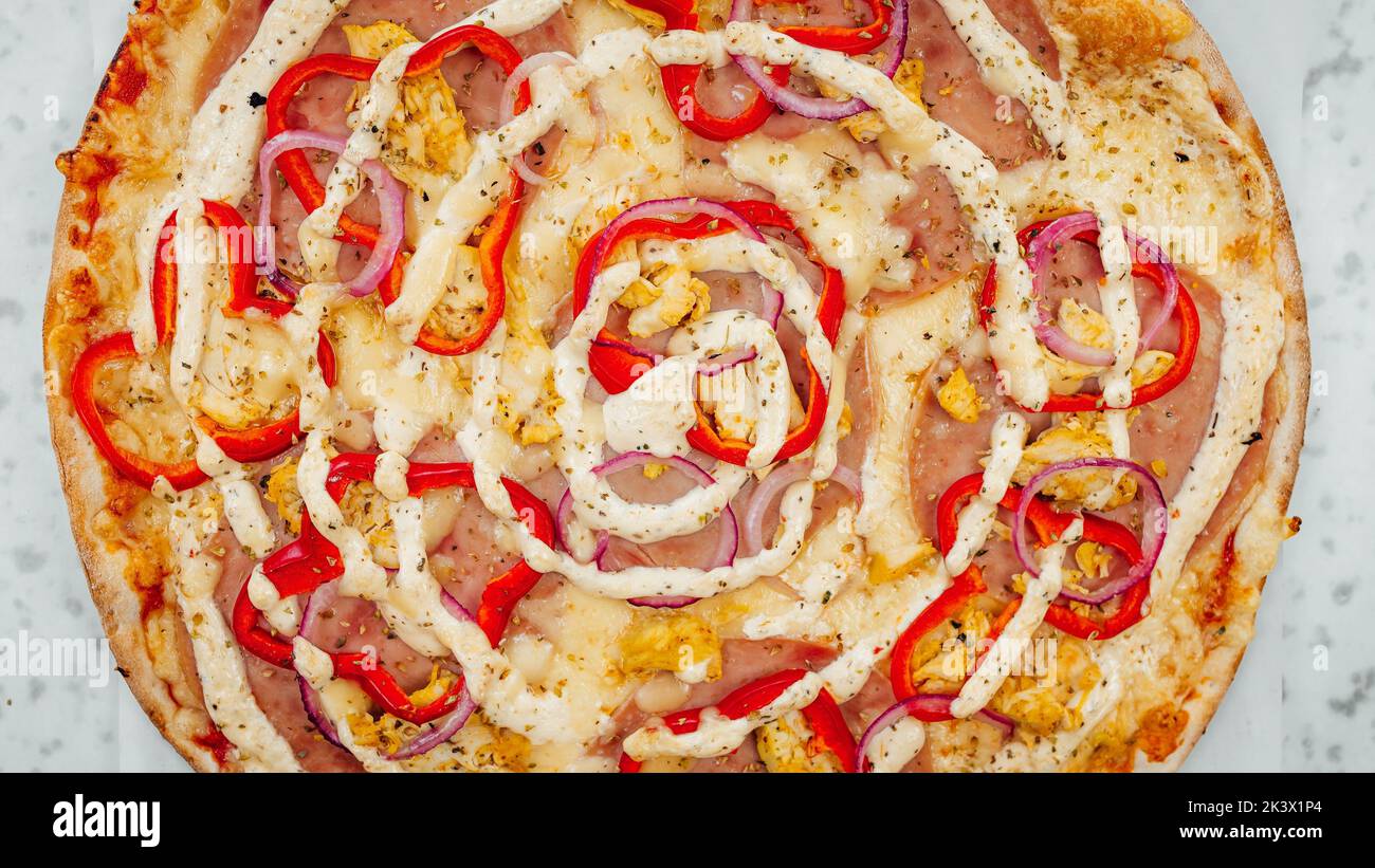 Une vue rapprochée de dessus de pizza au jambon et à l'oignon avec poivron rouge et sauce Banque D'Images