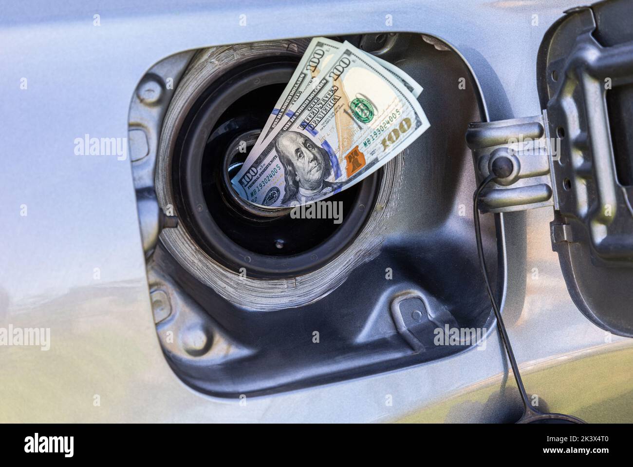 Billets de banque en dollars provenant du réservoir de gaz d'une voiture . Photo du concept de la hausse du prix du carburant Banque D'Images