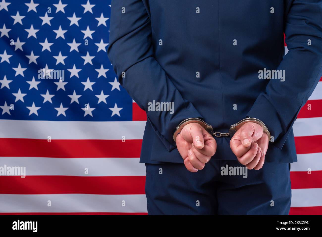 Homme d'affaires en costume veste menotté avec drapeau des états-unis en arrière-plan. Corruption politique et financière en Amérique Banque D'Images