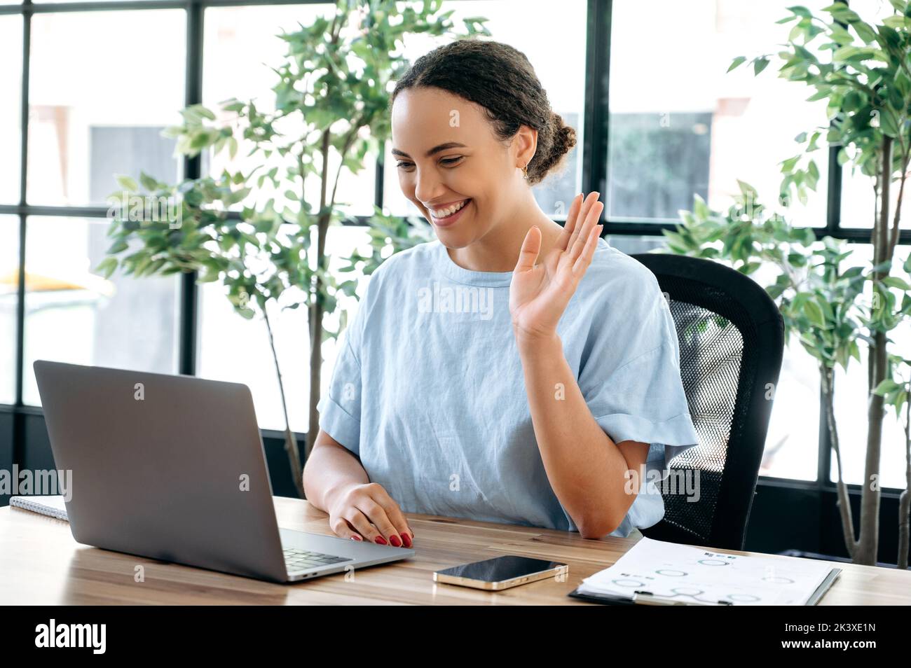 Positive belle femme brésilienne ou latino réussie, assis à un bureau