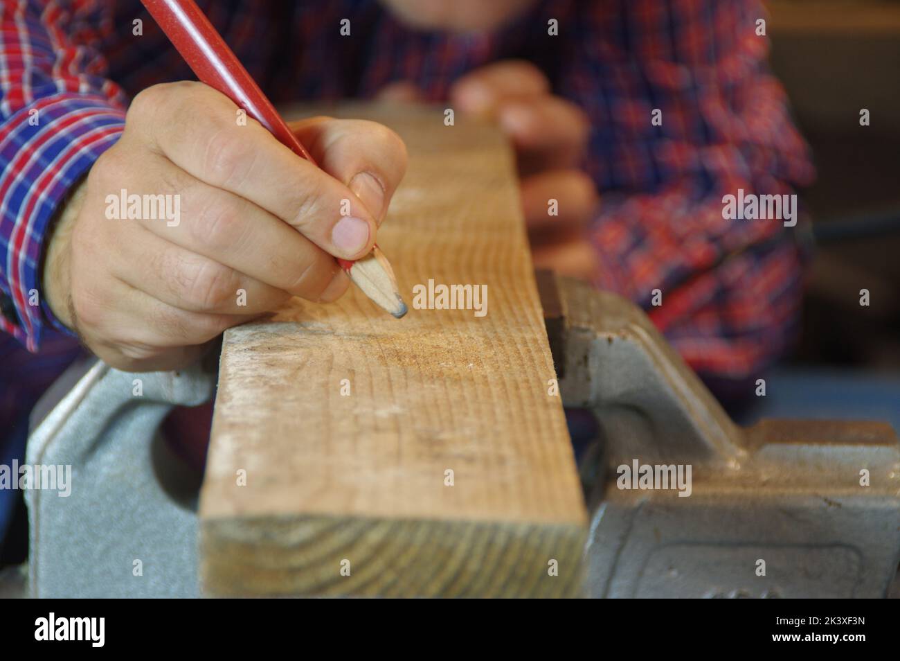 Dans l'atelier, Carpenter prépare une planche à découper brute. Menuisier dans l'atelier de menuiserie. Un expert en profondeur et un artisan attentif se sont concentrés sur le travail. Banque D'Images