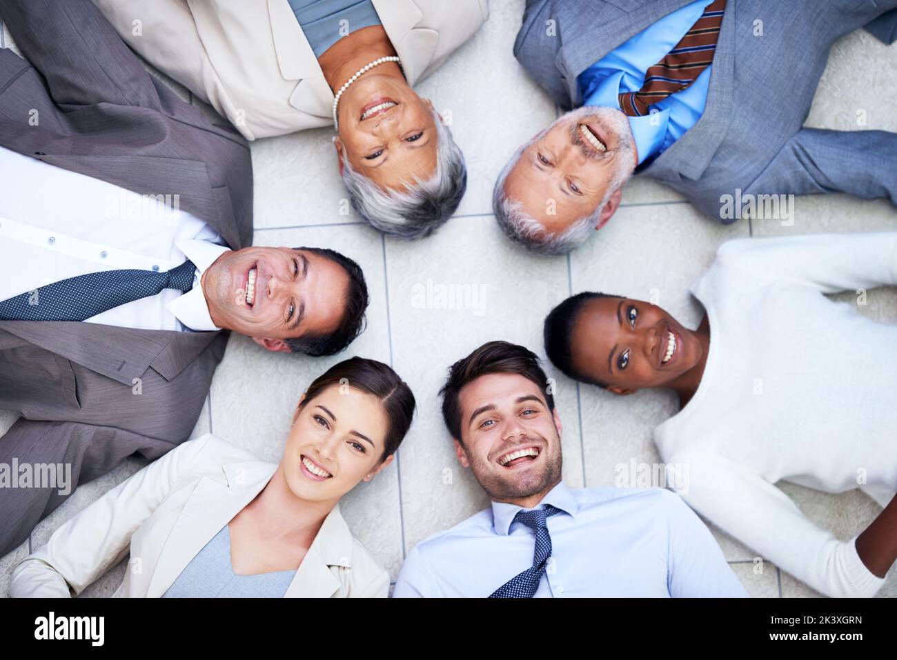 Voulez-vous rejoindre le cercle de confiance ? Portrait en grand angle d'un groupe de gens d'affaires divers qui se trouvent sur le sol dans un cercle. Banque D'Images