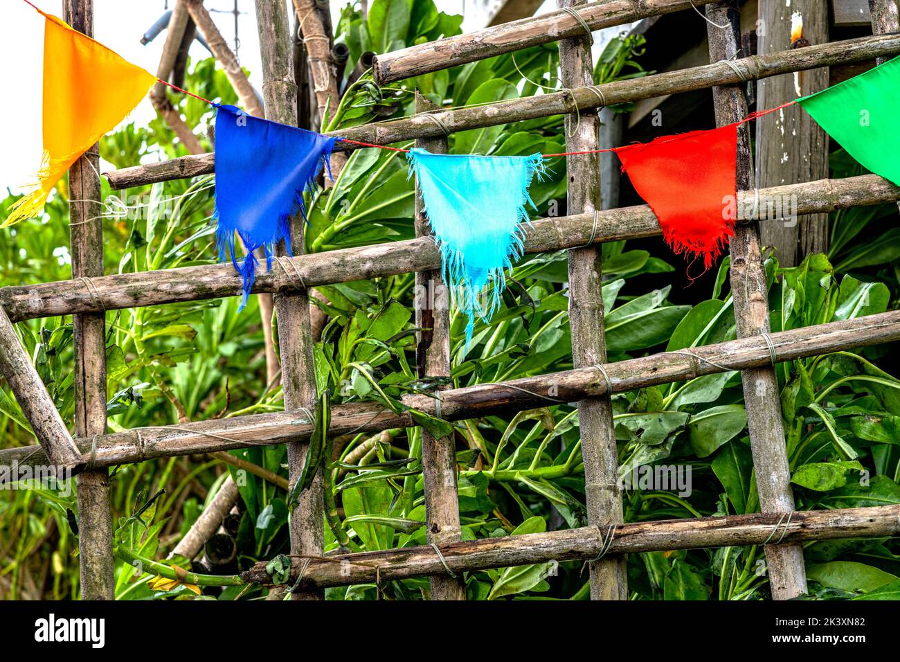 Structure de grille de bambou avec des drapeaux colorés qui pendent d'eux mais ils un temps battu, le vent déchiré. Banque D'Images