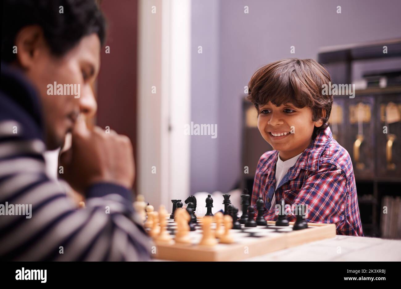 Pensez aussi dur que vous voulez. Un père et un fils jouant aux échecs à la maison. Banque D'Images