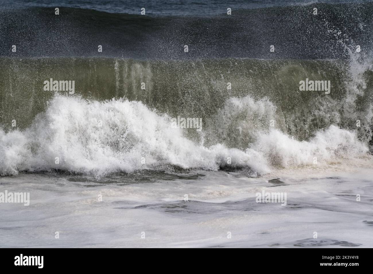 Les vagues déferlent, puis s'écrachent sur la rive où elles s'écraseront, jetant des jets dans l'air. Banque D'Images