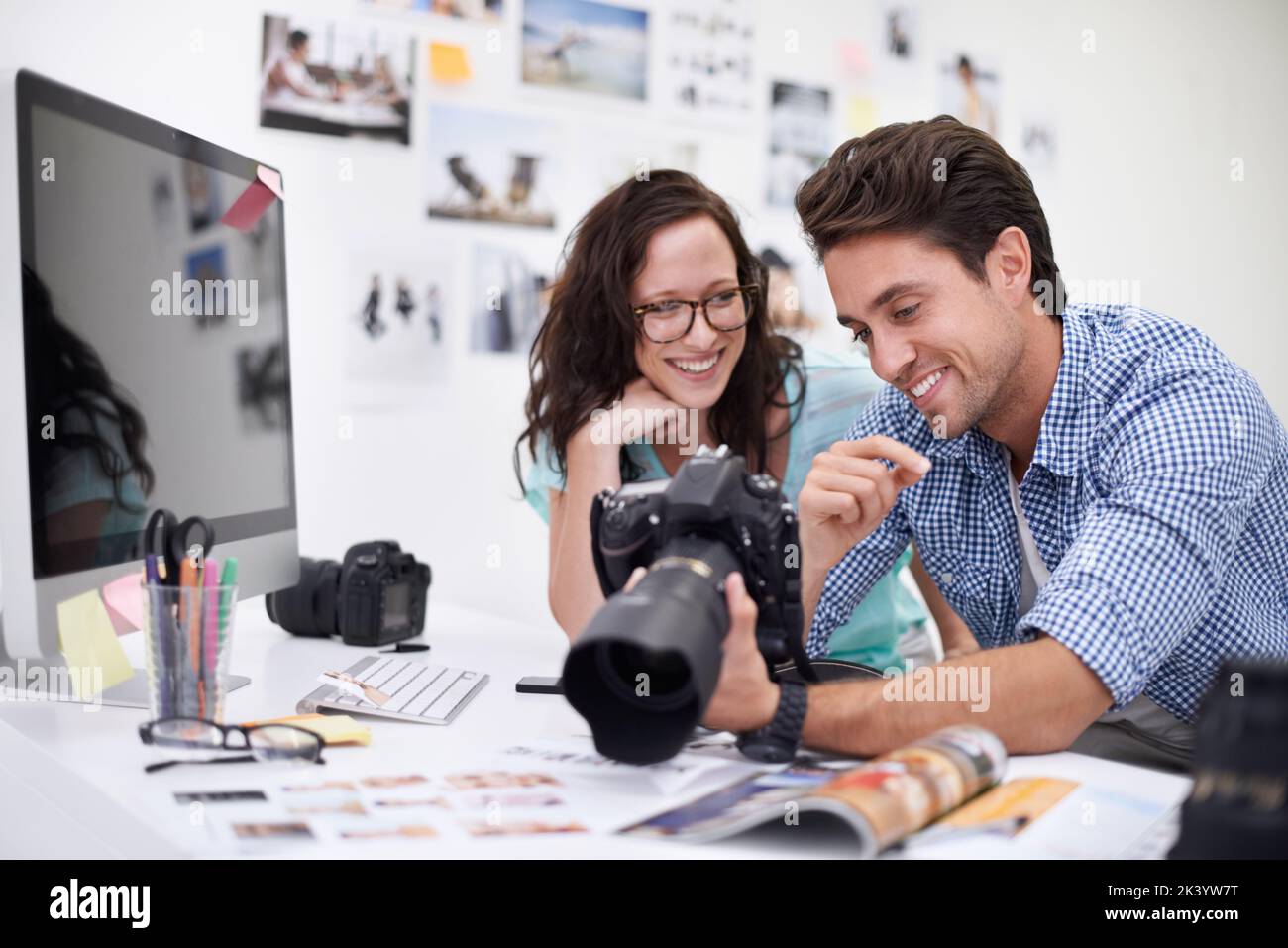Choisir l'image parfaite... deux jeunes photographes regardant des photos sur un appareil photo numérique dans leur studio. Banque D'Images