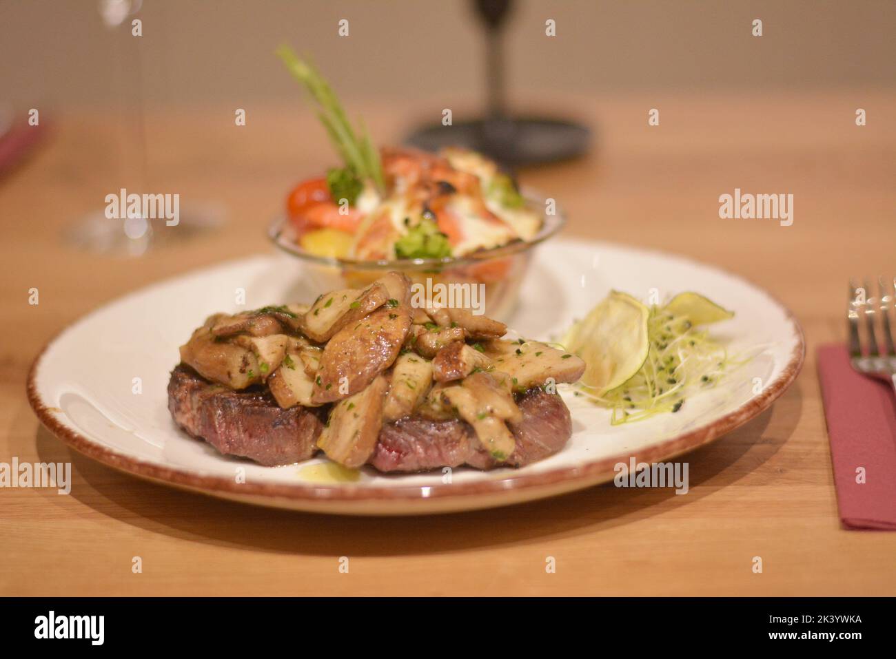 Délicieux steak de bœuf recouvert de champignons sautés. Garnir de pommes de terre gratin au et de germe de blé. Banque D'Images
