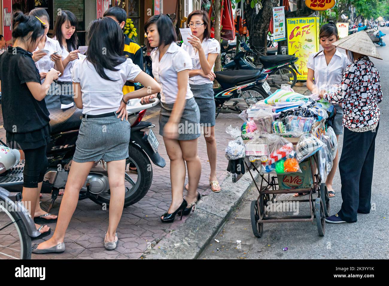 Jeune fille étudiante vietnamienne en uniforme avec un beleur de rue, Hai Phong, Vietnam Banque D'Images