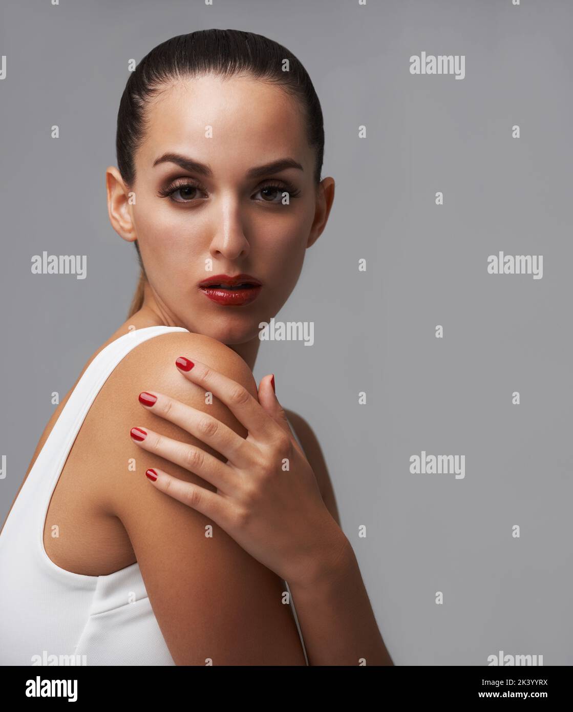 Sassy dans la scarlet. Portrait studio d'une jeune femme portant un rouge à lèvres et un vernis à ongles. Banque D'Images