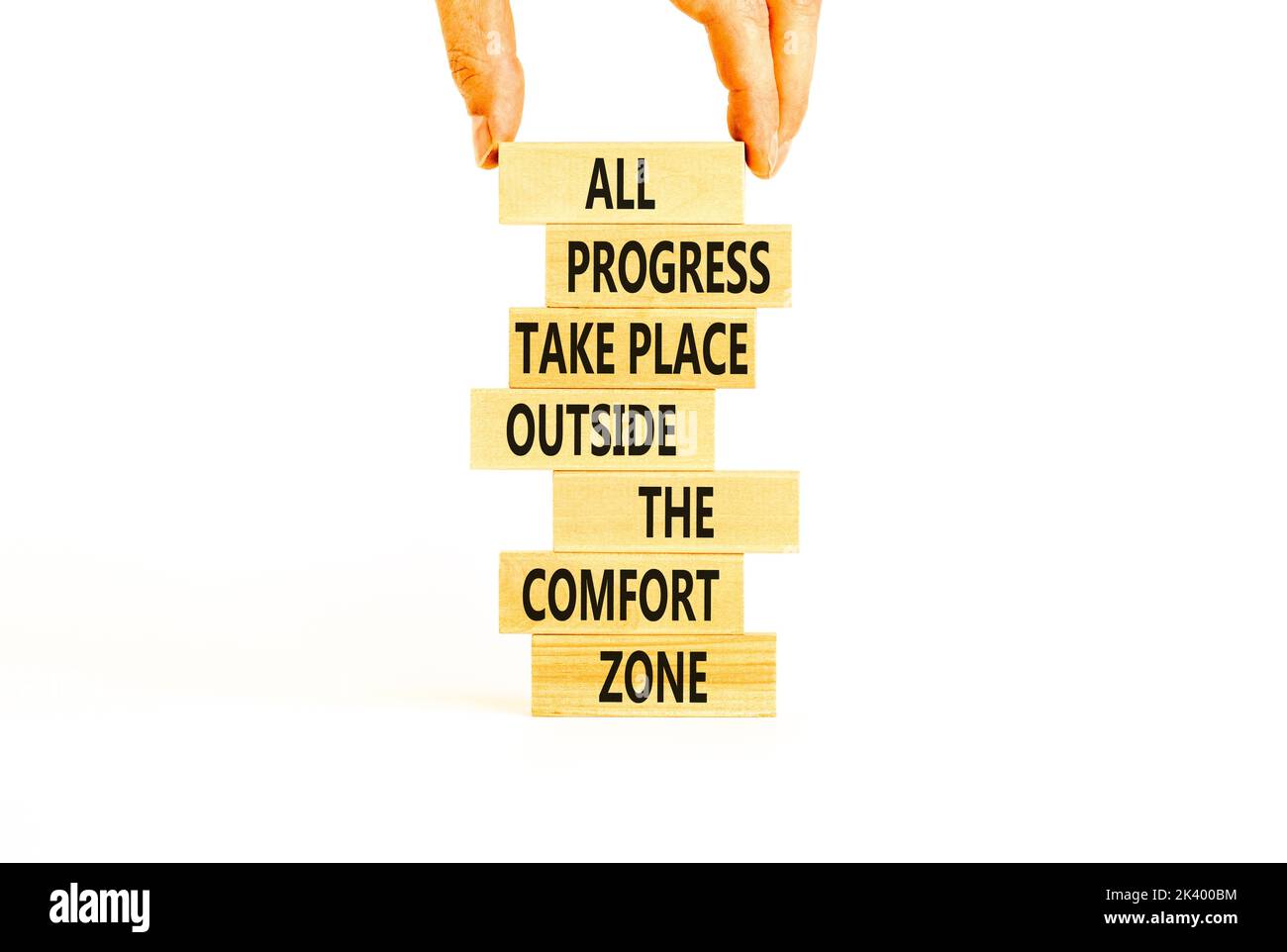 Symbole de progression. Mots de concept tous les progrès ont lieu en dehors de la zone de confort sur des blocs de bois sur un magnifique fond blanc. Main d'homme d'affaires. Unité commerciale Banque D'Images