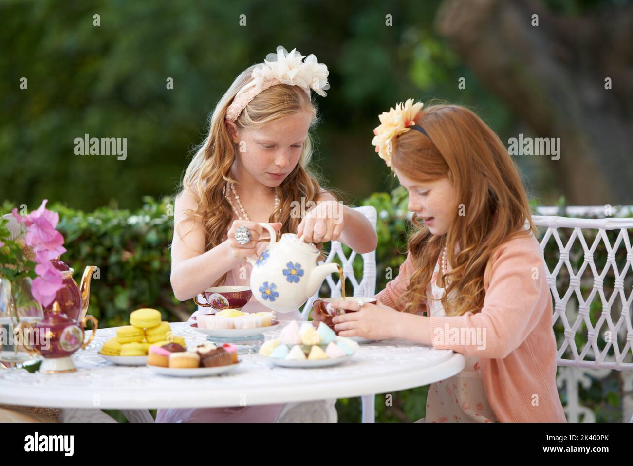 Avoir une fête de thé de make-Believe. Deux jeunes filles ayant une fête de thé dans l'arrière-cour. Banque D'Images