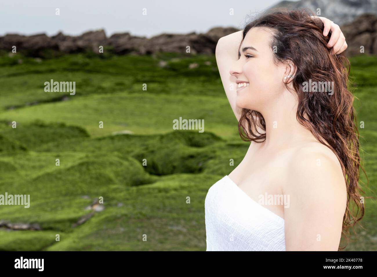 femme sur la côte avec robe blanche tenant ses cheveux Banque D'Images