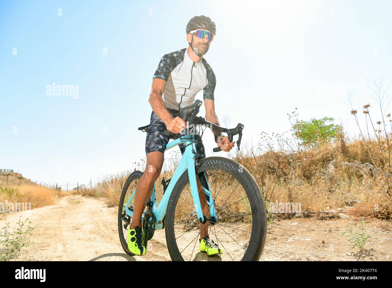 Cycliste pédalant en plein air avec tout son équipement de sécurité : casque, lunettes de soleil, par une journée ensoleillée Banque D'Images