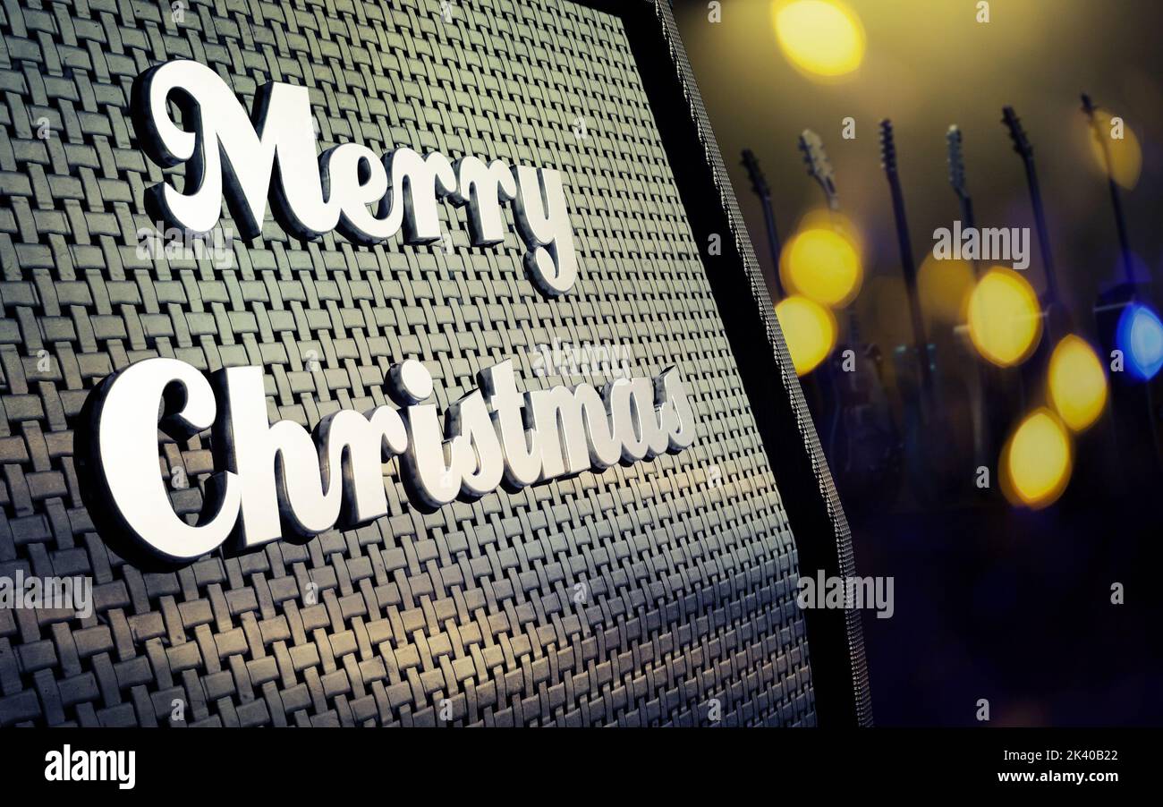 Gros plan d'un ampli guitare avec badge Merry Christmas et lumières de Noël floues, guitares floues en arrière-plan, rendu 3D Banque D'Images