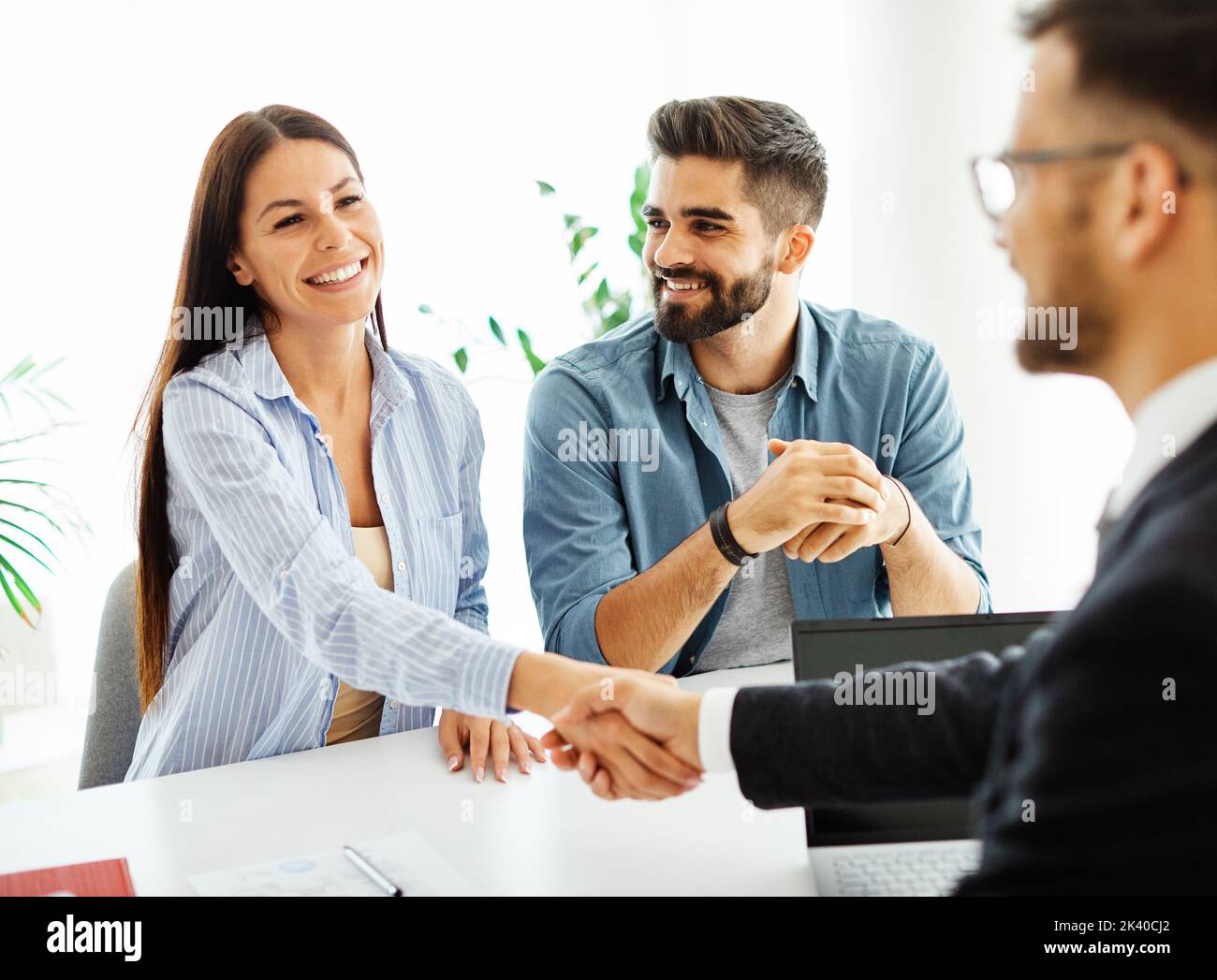 jeune couple qui tremble les mains traiter contrat immobilier investissement bureau d'affaires agent d'accord Banque D'Images